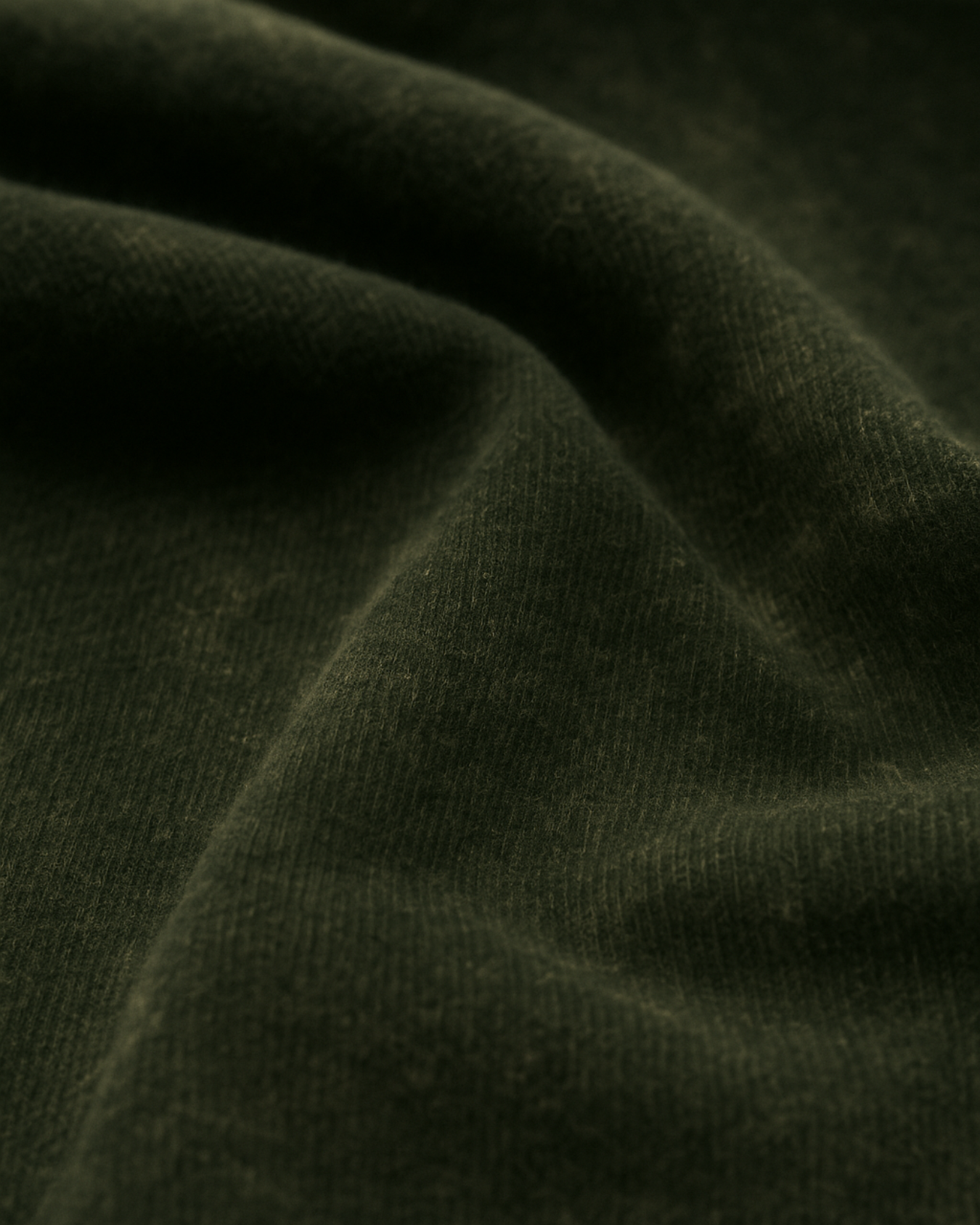 Textured closeup of olive green acid-wash cotton fabric – authentic look